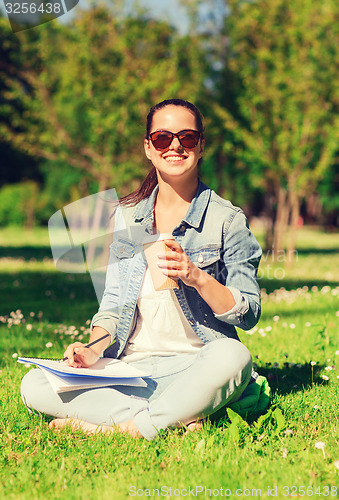 Image of smiling young girl with notebook and coffee cup