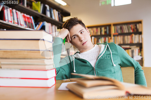 Image of bored student or young man with books in library