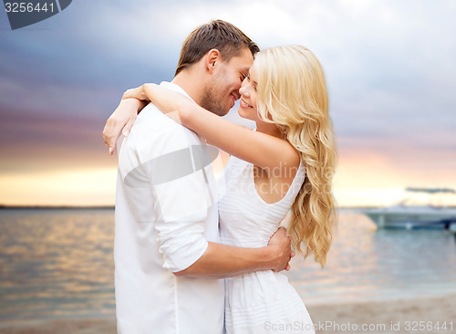 Image of happy couple hugging over sunset at summer beach