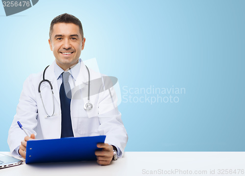 Image of happy doctor with clipboard over blue background