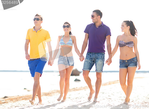 Image of group of happy friends walking along beach