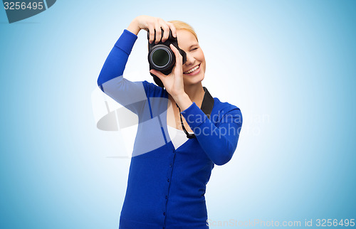 Image of smiling woman taking picture with digital camera