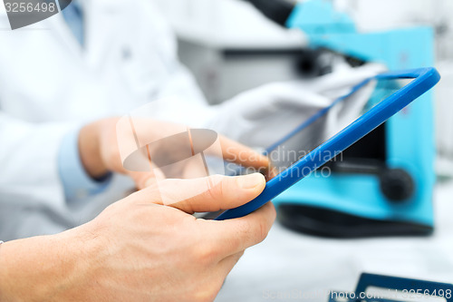 Image of close up of scientists hands with tablet pc in lab