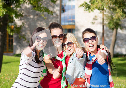 Image of happy teenage girls showing thumbs up at campus