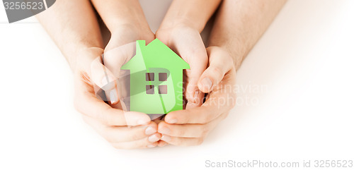 Image of man and woman hands with green paper house