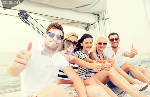 Image of smiling friends on yacht showing thumbs up