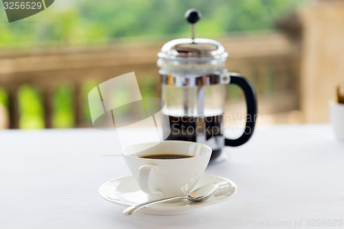 Image of cup of coffee and french press on table 