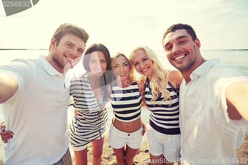 Image of happy friends on beach and taking selfie