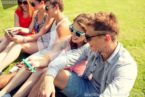 Image of smiling friends with smartphone making selfie