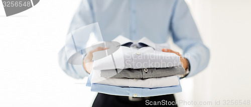 Image of close up of businessman holding folded shirts