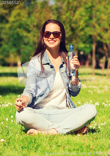 Image of smiling young girl with bottle of water in park