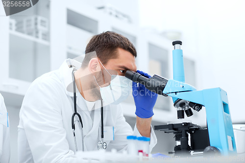 Image of young scientist looking to microscope in lab