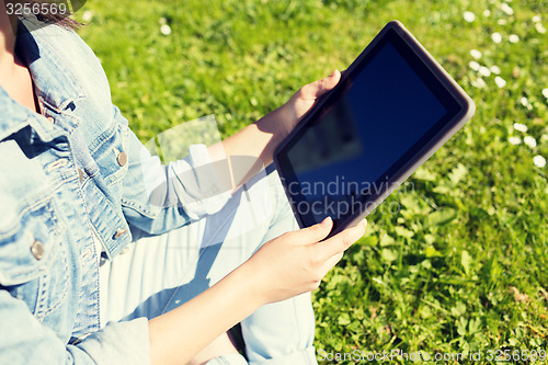 Image of close up of girl with tablet pc sitting on grass