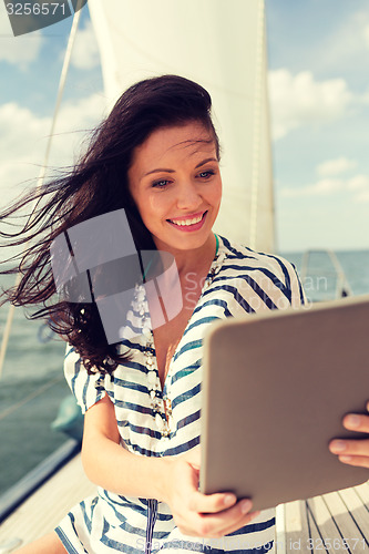 Image of smiling woman sitting on yacht with tablet pc