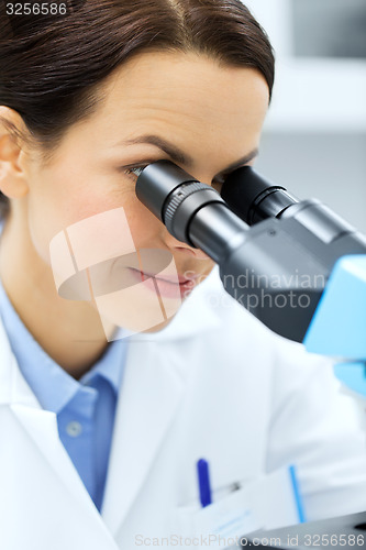 Image of close up of scientist looking to microscope in lab