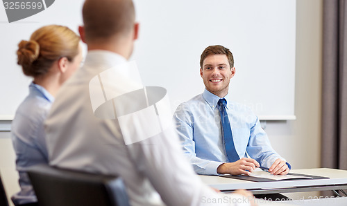 Image of group of smiling businesspeople meeting in office