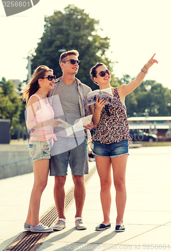 Image of smiling friends with map and city guide outdoors