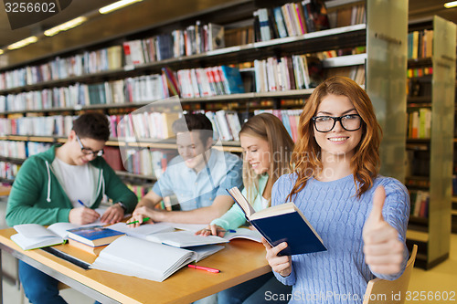 Image of happy student girl showing thumbs up in library