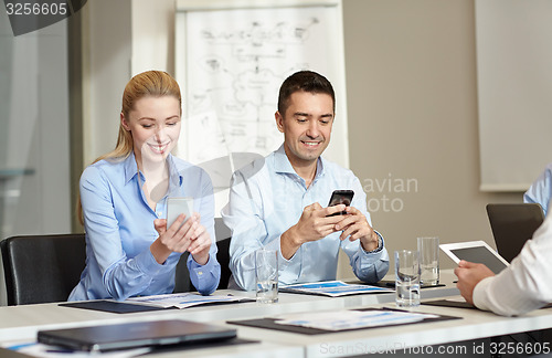 Image of smiling business people with smartphones in office