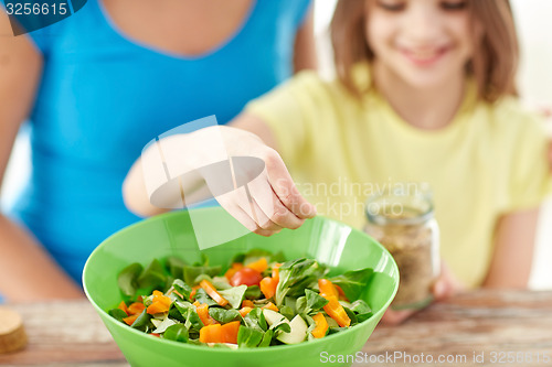 Image of close up of happy family cooking salad in kitchen