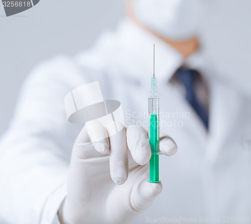 Image of male doctor holding syringe with injection