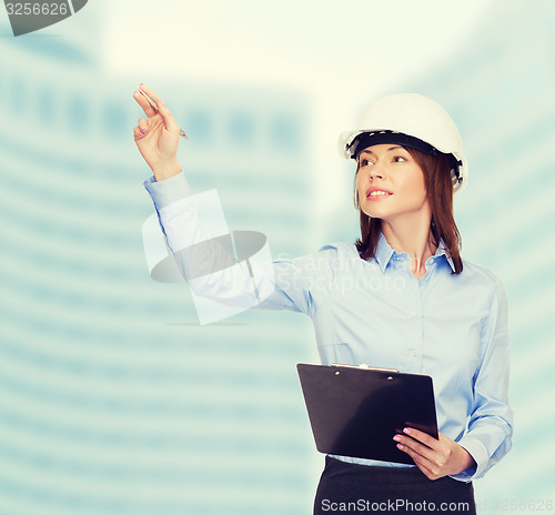 Image of smiling businesswoman in helmet with clipboard