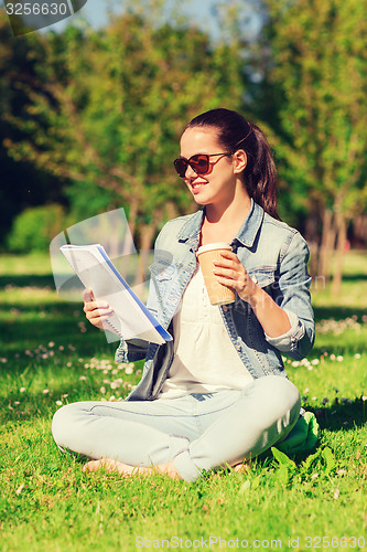 Image of smiling young girl with notebook and coffee cup