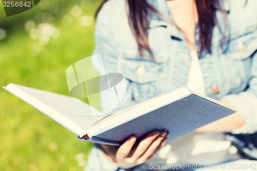 Image of close up of young girl with book in park