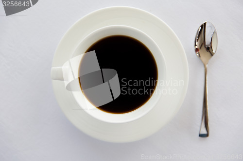 Image of cup of black coffee with spoon and saucer on table