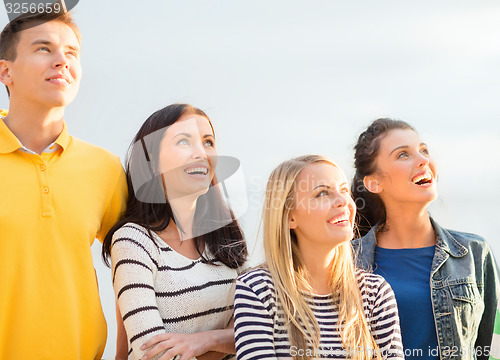 Image of group of happy friends looking up on beach