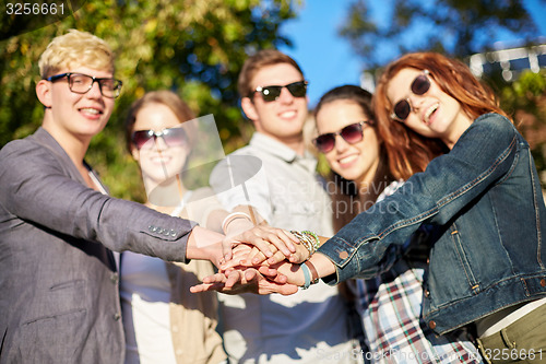 Image of close up of teenage friends with hands on top