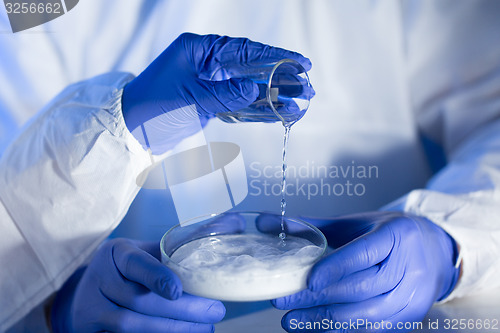 Image of close up of scientists hands with chemicals in lab