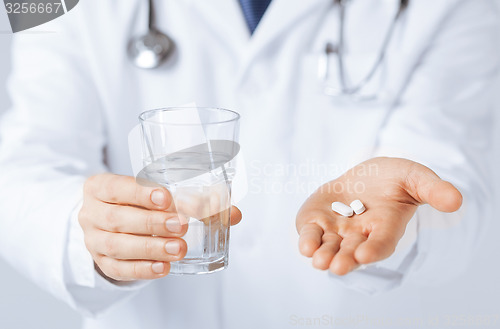 Image of doctor hands giving white pills and glass of water