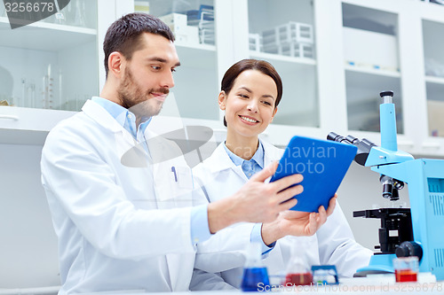 Image of scientists with tablet pc and microscope in lab