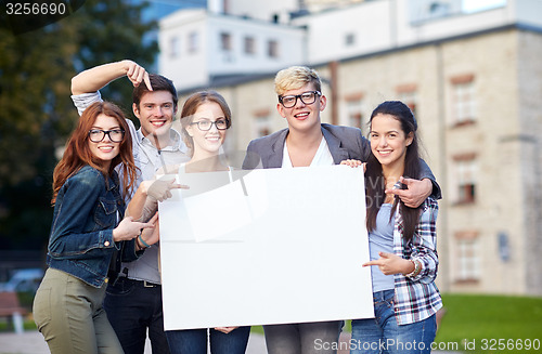 Image of happy teenage students holding white blank board