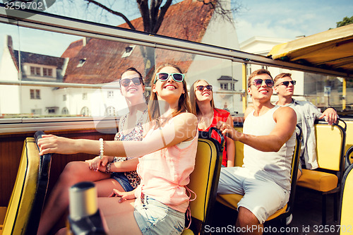 Image of group of smiling friends traveling by tour bus