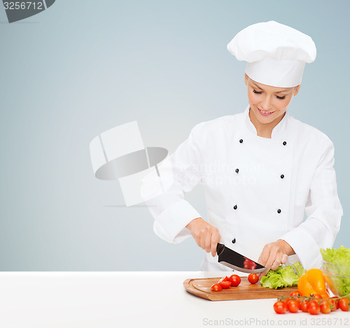 Image of smiling female chef chopping vegetables