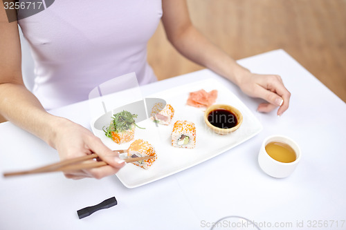 Image of close up of woman eating sushi at restaurant