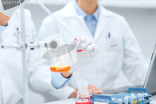 Image of close up of scientists filling test tube in lab