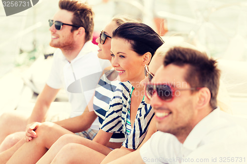 Image of smiling friends sitting on yacht deck