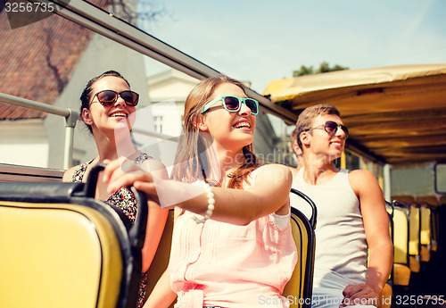 Image of group of smiling friends traveling by tour bus