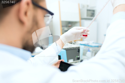 Image of close up of scientist with tube and pipette in lab