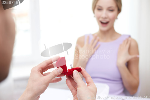 Image of excited young woman and boyfriend giving her ring