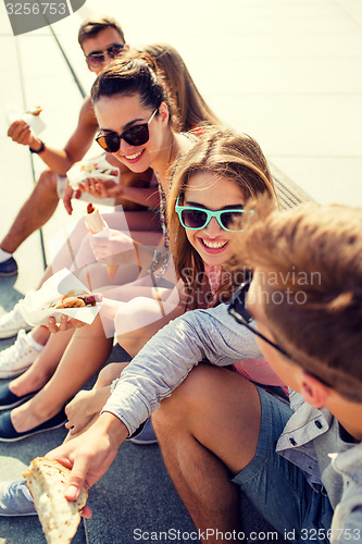Image of group of smiling friends sitting on city square