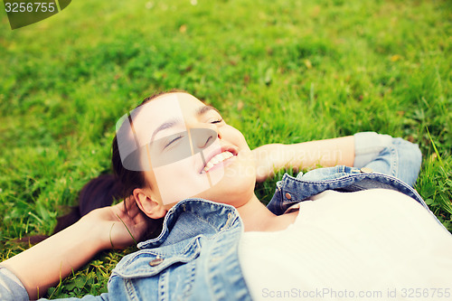 Image of smiling young girl with closed eyes lying on grass