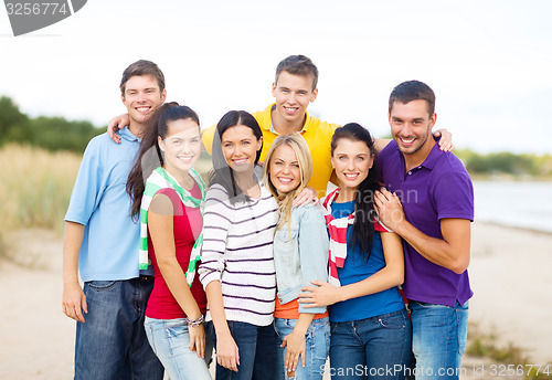 Image of group of happy friends hugging on beach