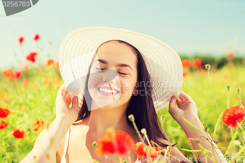 Image of smiling young woman in straw hat on poppy field