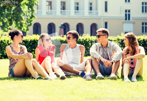 Image of group of smiling friends outdoors sitting on grass