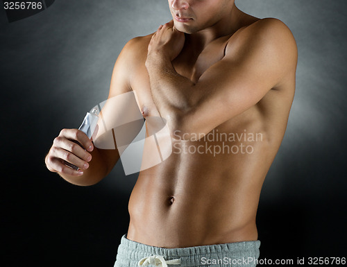 Image of young male bodybuilder applying pain relief gel