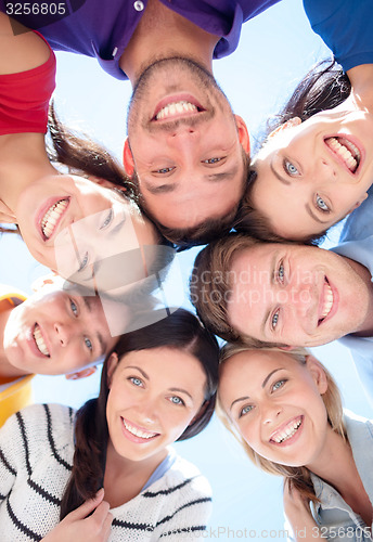 Image of smiling friends in circle on summer beach